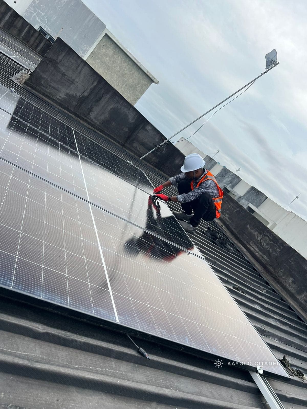 A Kayglo installer torquing down a rooftop panel array above the office complex.