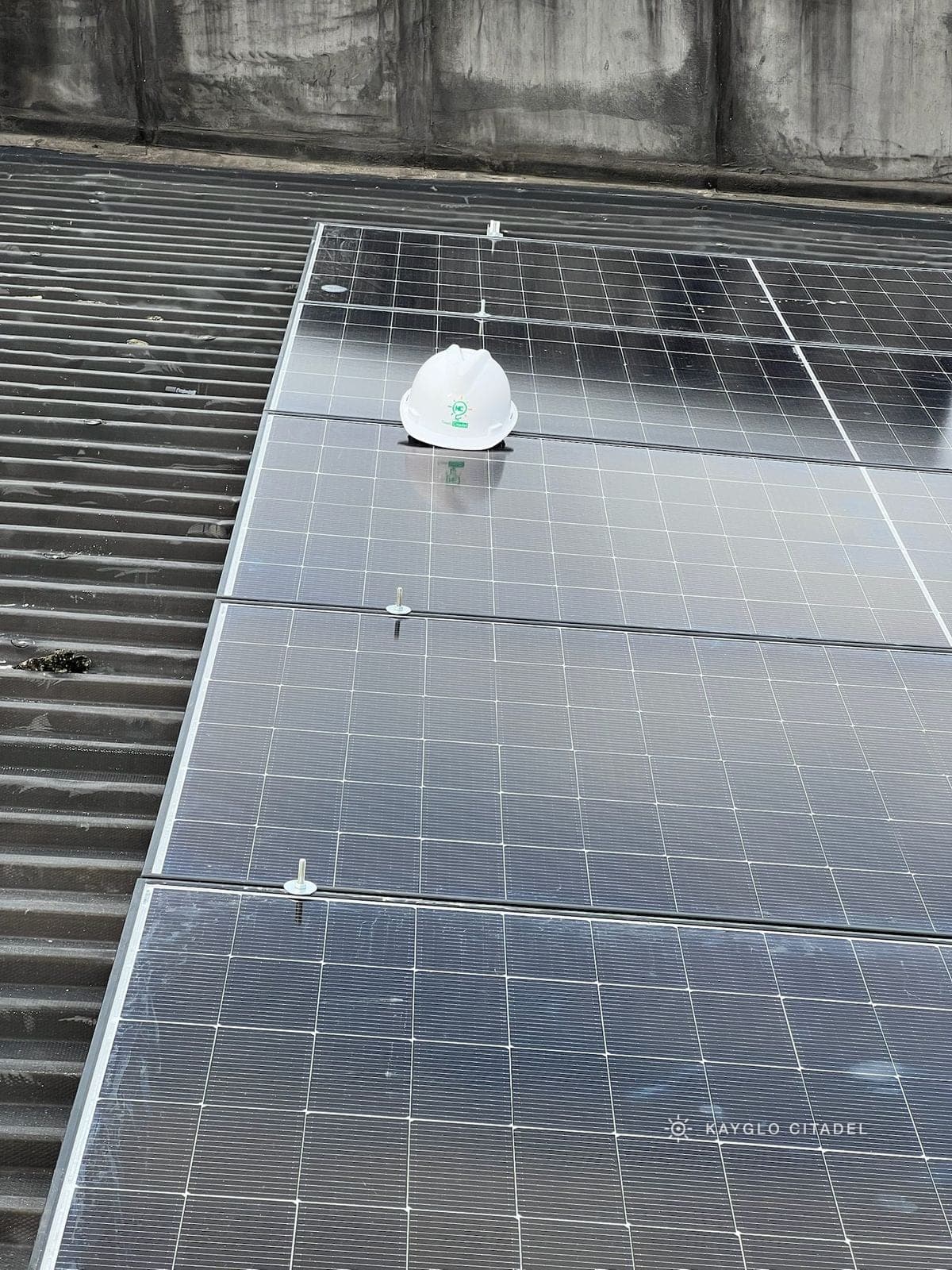 A finished commercial rooftop array on a metal roof, with a Kayglo hard hat resting on a panel.
